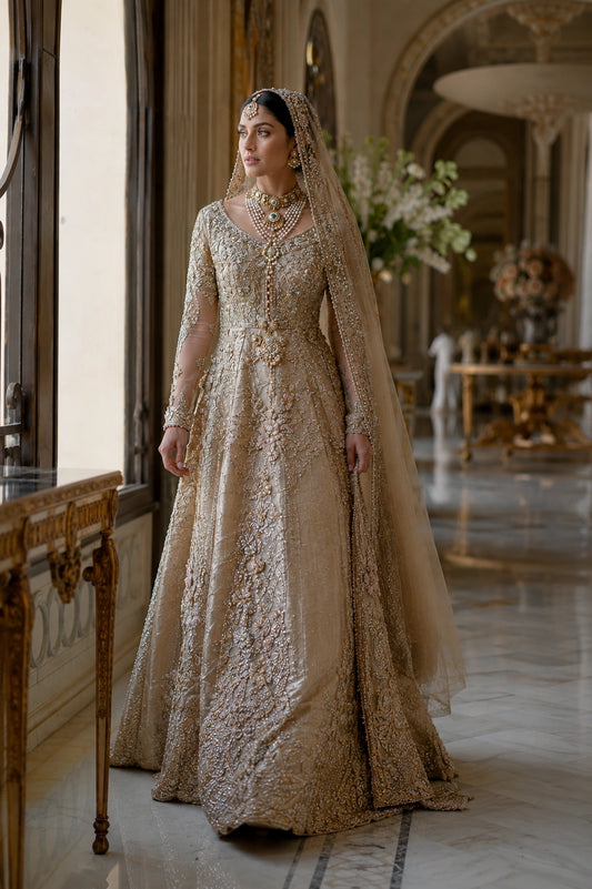 Model wearing a champagne gold tissue silk bridal gown with intricate hand embroidery and embellished organza veil in a luxury palace-inspired setting by Miraam.