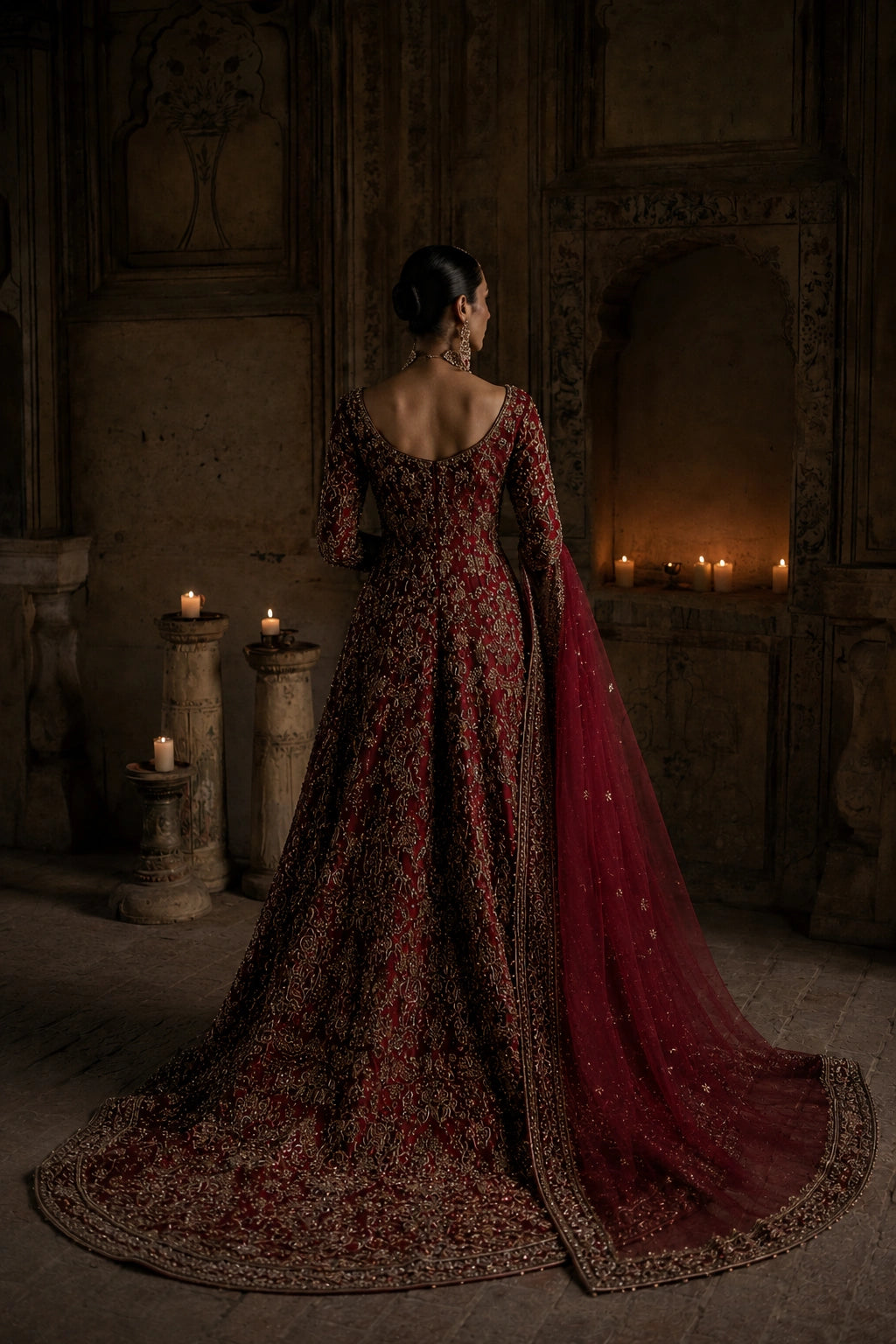 Model wearing a crimson raw silk bridal couture gown with intricate antique gold embellishment and embroidered organza dupatta in a regal heritage-inspired setting by Miraam.