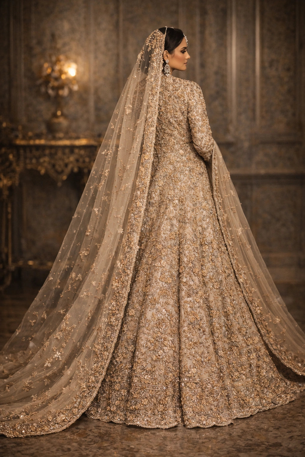 Bride wearing champagne embroidered bridal lehenga with long jacket and sheer dupatta in royal interior setting