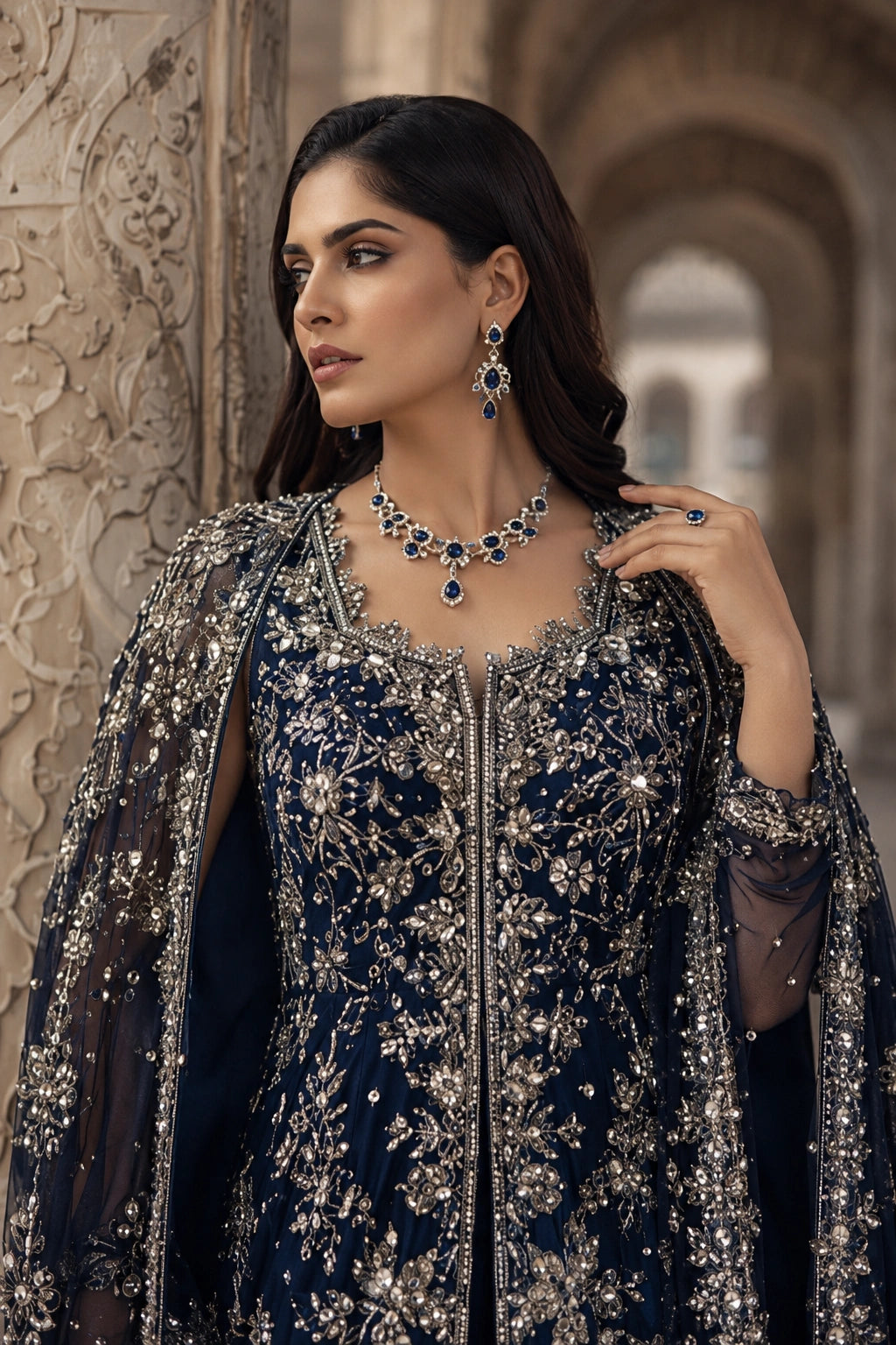 Woman wearing a navy blue sheesha silk embellished gown with attached embroidered organza cape by Miraam