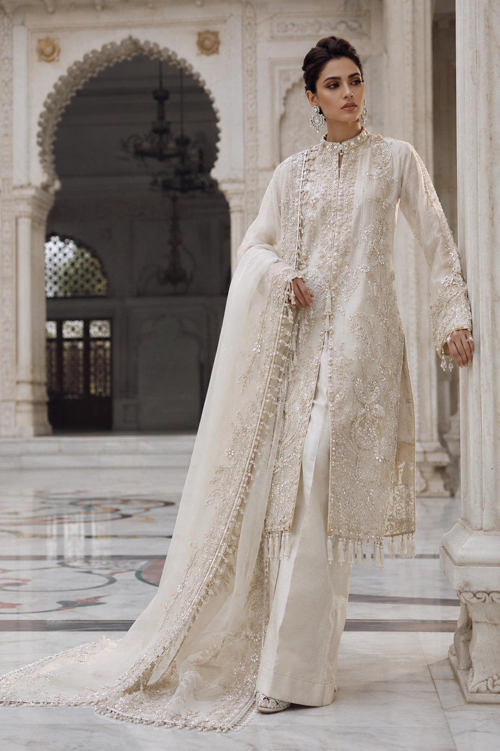Woman wearing an ivory raw silk embroidered shirt with wide-leg pants and embellished organza dupatta by Miraam