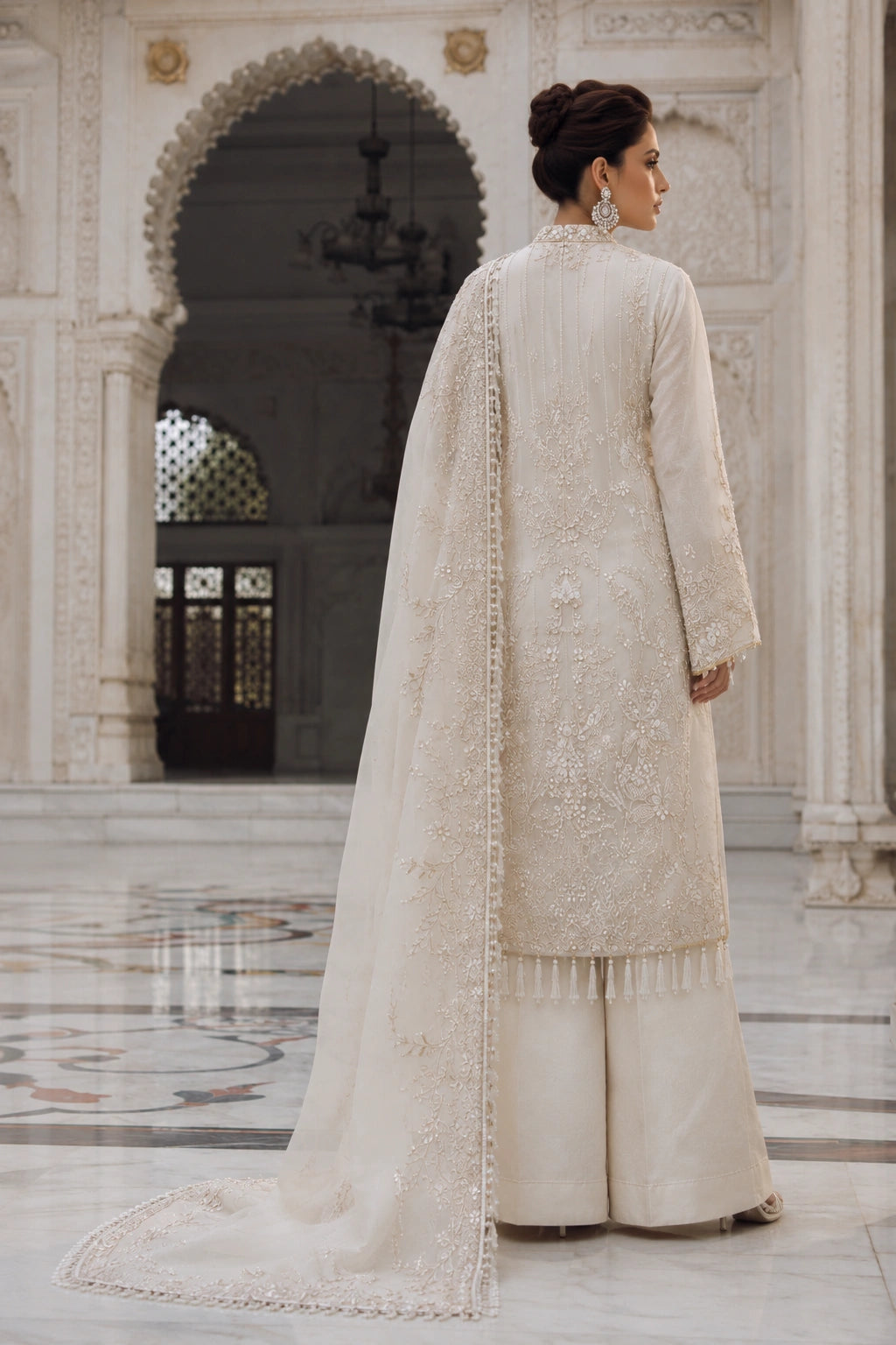Woman wearing an ivory raw silk embroidered shirt with wide-leg pants and embellished organza dupatta by Miraam