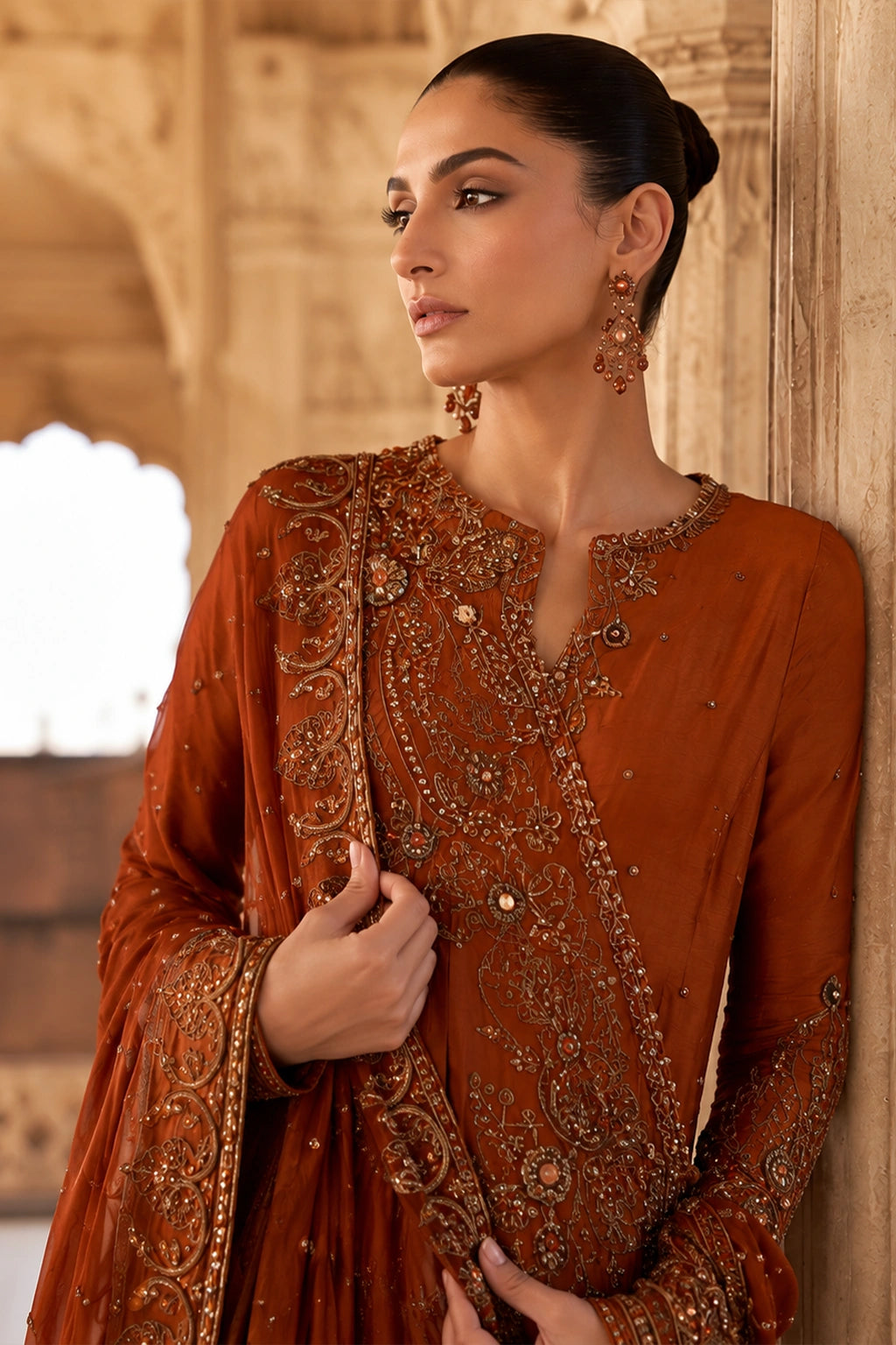 Woman wearing an amber raw silk angrakha shirt with embellished organza dupatta by Miraam