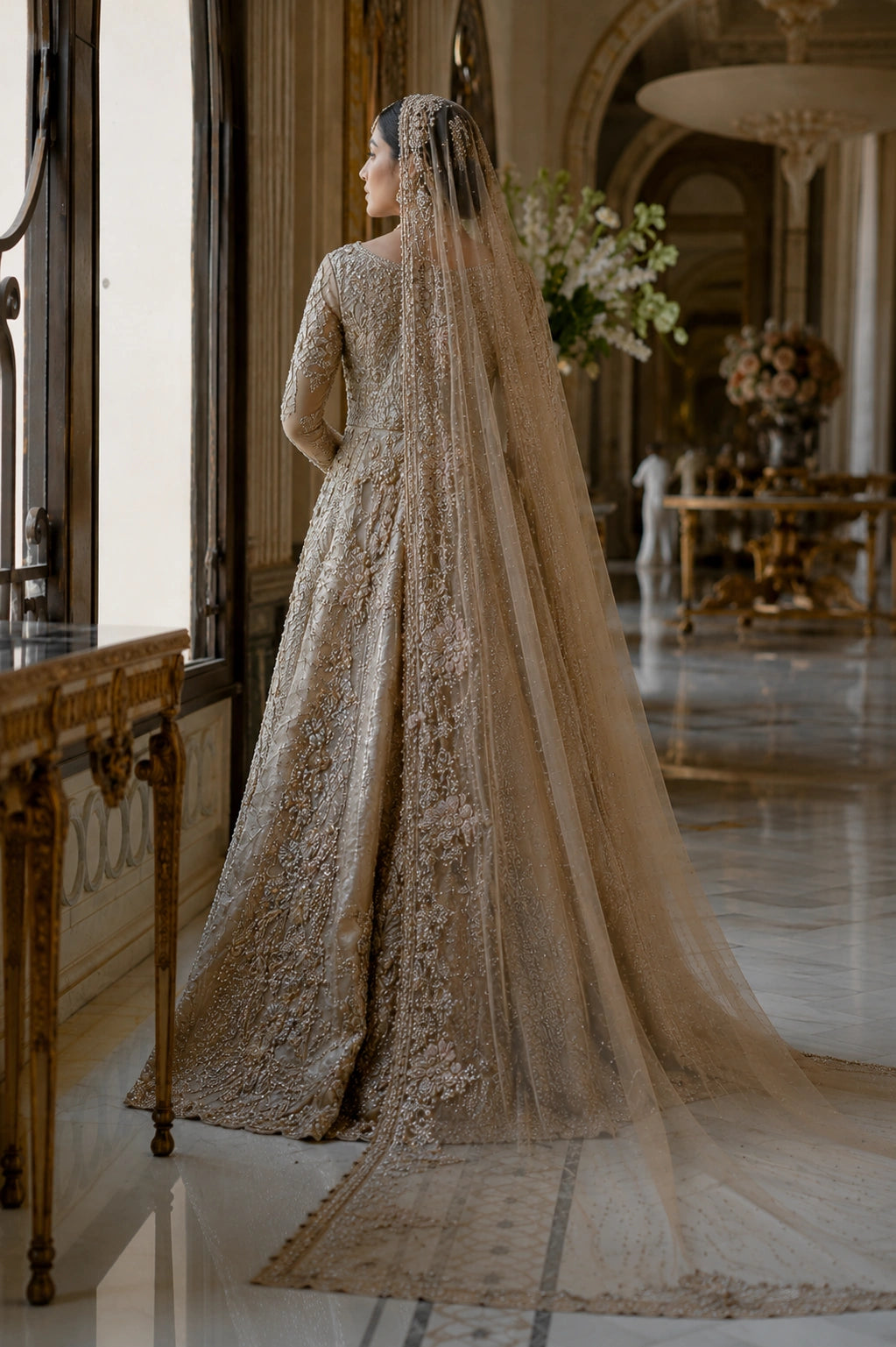 Model wearing a champagne gold tissue silk bridal gown with intricate hand embroidery and embellished organza veil in a luxury palace-inspired setting by Miraam.