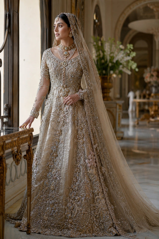 Model wearing a champagne gold tissue silk bridal gown with intricate hand embroidery and embellished organza veil in a luxury palace-inspired setting by Miraam.