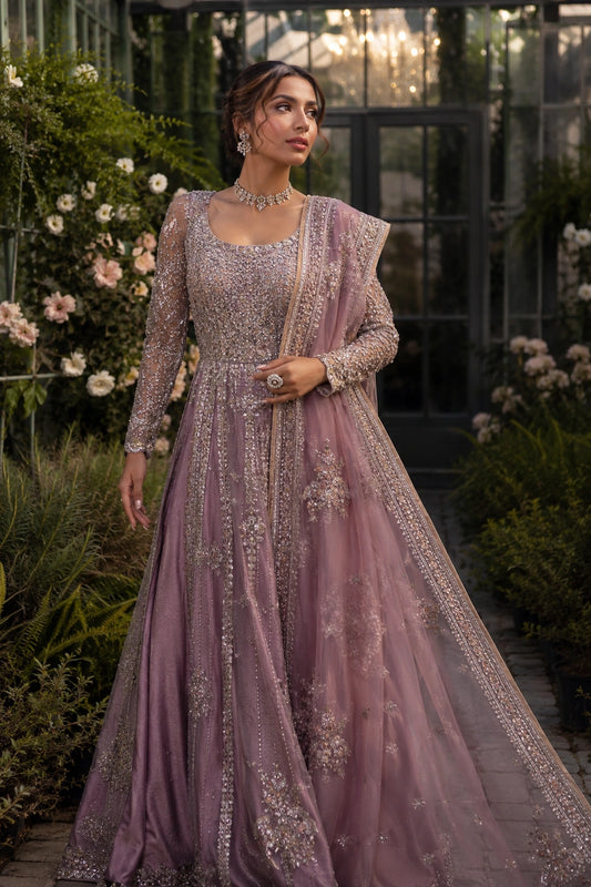 Model wearing a mauve sheesha silk bridal pishwas with intricate embellishment and embroidered organza dupatta in a luxury garden-inspired setting by Miraam.