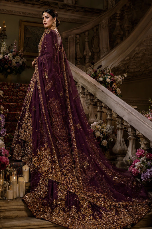 Model wearing a deep plum raw silk bridal couture gown with intricate antique gold embellishment and a heavily embroidered organza veil in a regal palace-inspired setting by Miraam.